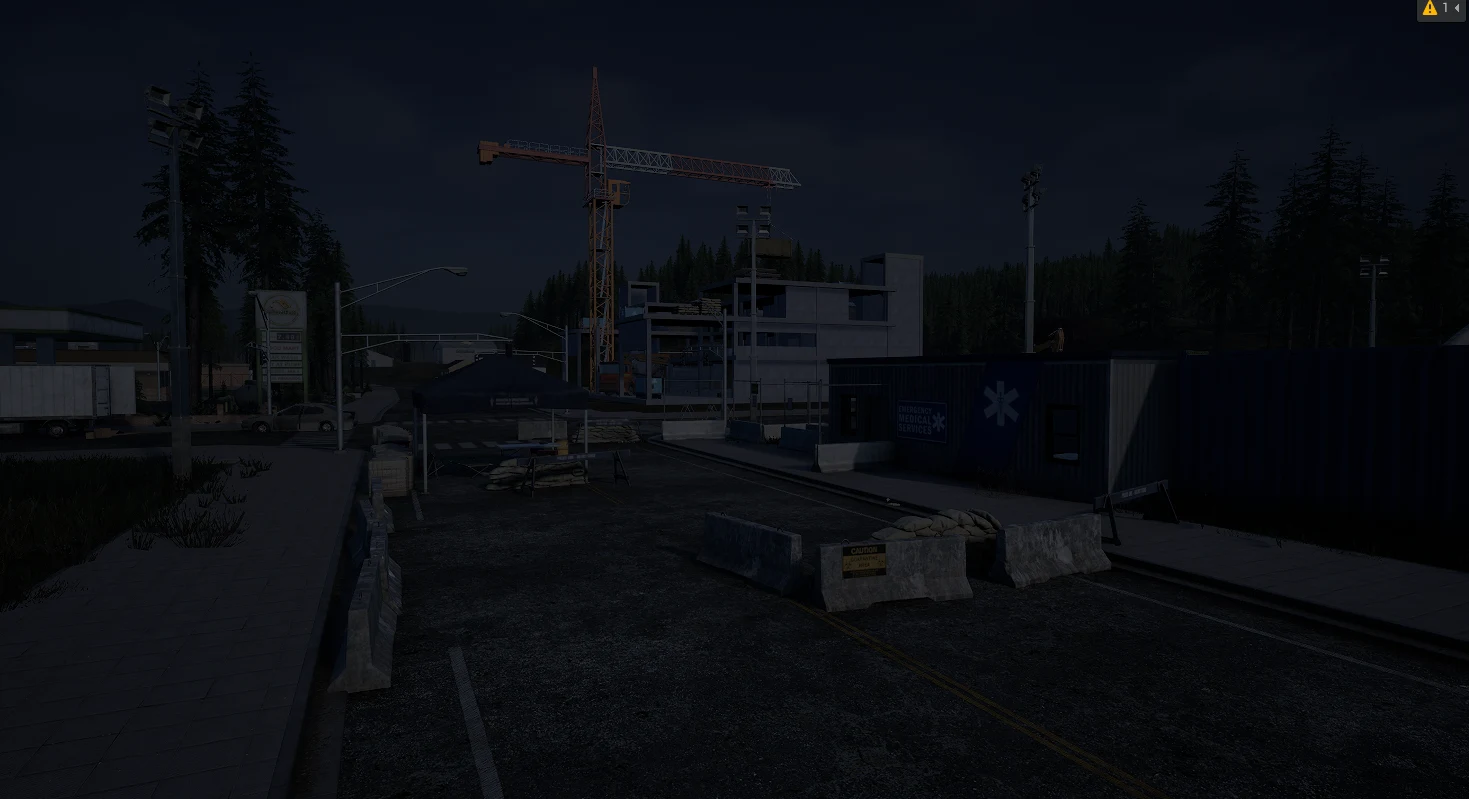 A dark checkpoint street with concrete barriers, medical containers and a construction crane